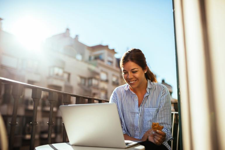 Mujer trabajando frente a un portátil en un balcón  